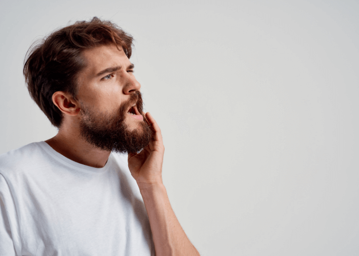 man holding his jaw due to pain