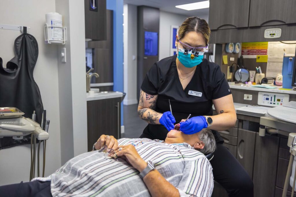 Hygienist cleaning a patient's teeth at keith + associates dentistry in Mission, KS.